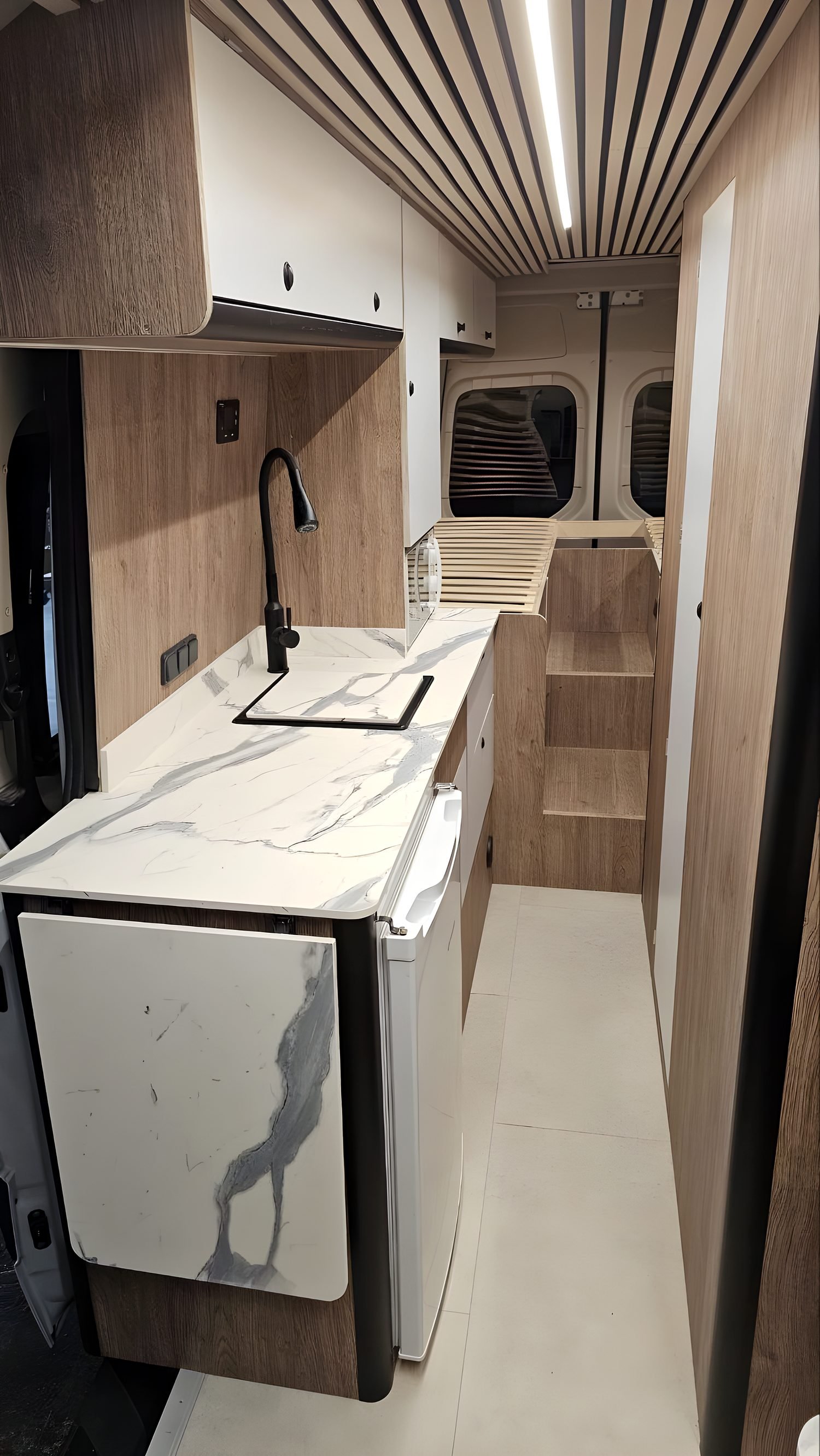 Cocina de una camper con encimera de mármol, fregadero y escalón de acceso