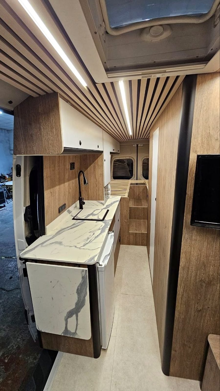 Cocina de una camper con encimera de mármol y muebles a medida